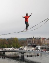 عضو في جمعية الحبل المشدود الدنماركية يسير في خط طوله 160 مترًا معلقًا على ارتفاع 15 مترًا فوق المرفأ في كوبنهاغن، الدنمارك.    (رويترز)