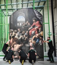 عمال يحملون لوحة كبيرة في موقع ترميم لوحات كاتدرائية نوتردام دي باريس  (ا ف ب)