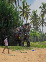 صبي يمشي أمام عمل فني يشبه توسكر تم بناؤه بالقمامة التي جمعتها الفنانة السريلانكية لاليث سيناناياكي من الشواطئ المحلية، على شاطئ في سريلانكا.  ا ف ب 
