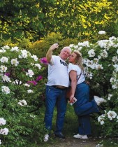 زوجان يلتقطان صورة سيلفي بالقرب من شجيرات الفاوانيا المزهرة في الحديقة النباتية في كييف. (ا ف ب)