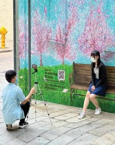 شاب يلتقط صورا لفتاة تتظاهر بالجلوس على مقعد مرسوم في لوحة جدارية في منطقة وسط هونغ كونغ - ا ف ب