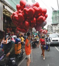باعة يبيعون بالونات على شكل قلب للعملاء في شارع للزهور خلال عيد الحب في مانيلا  - ا ف ب