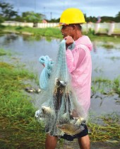 رجل يحمل شبكة بها الأسماك التي تم صيدها في مياه الفيضانات بعد هطول أمطار غزيرة في مقاطعة ناراثيوات جنوب تايلاند -ا ف ب
