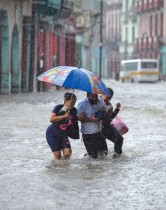 عائلة تتجول في شارع غمرته المياه في هافانا نتيجة أمطار غزيرة من بقايا إعصار أجاثا. ا ف ب