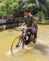 شابان يركبان دراجة في شارع غمرته المياه في منطقة جامبونج ميوناساه في شمال آتشيه، إندونيسيا -ا ف ب 