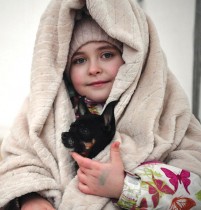 طفلة أوكرانية مع كلبها تنتظر بعد نقلها في مخيم للمنظمة الدولية للهجرة بعد عبور الحدود الأوكرانية البولندية في ميديكا ، جنوب شرق بولندا.  ا ف ب