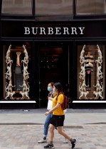 فتاتان ترتديان أقنعة واقية وتسيران بالقرب من متجر بربري في كوفنت جاردن في لندن، بريطانيا.  رويترز