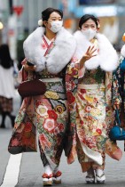 فتاتان ترتديان الكيمونو والأقنعة الواقية في طريقهما لحضور احتفال يوم بلوغ سن الرشد، وسط تفشي مرض فيروس كورونا COVID-19 ، في طوكيو.    رويترز