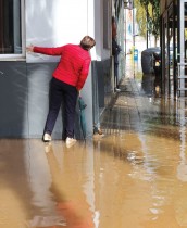 امرأة تحاول العبور عبر رصيف غمرته المياه، مع هطول أمطار غزيرة في مدينة الداية بإسبانيا. رويترز