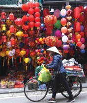 بائعة متجولة تدفع دراجتها عبر متجر يبيع الزينة في الحي القديم في هانوي، قبل رأس السنة القمرية الجديدة. ا ف ب