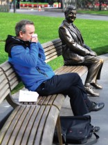 رجل يعطس وهو جالس بجوار تمثال لـ (مستر بين) في ليستر سكوير بلندن حيث ترتفع حالات الإصابة بفيروس كورونا. (رويترز)