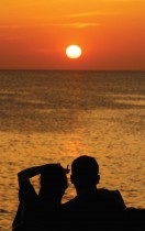 زوجان يشاهدان غروب الشمس من شرفة كازينو بالقرب من سان أنطونيو في جزيرة إيبيزا الإسبانية البليارية. رويترز