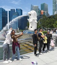 زوار يلتقطون صورا أمام تمثال الميرليون في خليج مارينا في سنغافورة (ا ف ب)