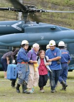 أفراد من قوات الدفاع عن النفس اليابانية يساعدون زوجين مسنين بعد أن تم إجلاؤهم بطائرة هليكوبتر عسكرية من منطقة كارثة بعد هطول أمطار غزيرة في محافظة كوماموتو.   (ا ف ب) 