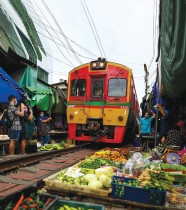 قطار ركاب يمر ست مرات يوميا عبر سوق ماي كلونج للسكك الحديدية في مقاطعة ساموت سونجكرام ، على بعد حوالي 80 كيلومترًا 5 ميلًا جنوب غرب بانكوك. ا ف ب