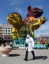 امرأة ترتدي قناع الوجه الواقي تمر أمام هيكل عملاق لسنجاب في ألماتي بعد أن أعلنت كازاخستان حالة الطوارئ كجزء من التدابير الوقائية ضد انتشار فيروس كورونا. رويترز