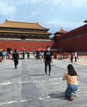 شاب يقف لالتقاط صورة عند مدخل مدينة في بكين، بعد أن خففت الحكومة بعض قيود كورونا مع استئناف عمل معظم المتاحف. ا ف ب
