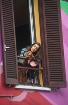 امرأة بجانبها كلبها تنظر من شرفة منزلها وتصفق للأطقم الطبية، لرفع الروح المعنوية أثناء أزمة فيروس كورونا، في ميلانو، إيطاليا. رويترز