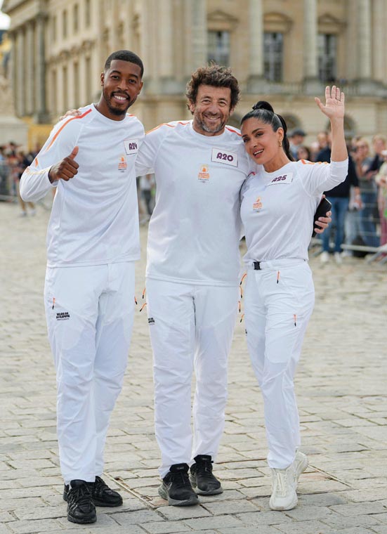 لاعب كرة القدم الفرنسي بريسنل كيمبيمبي والممثل الفرنسي باتريك برويل والممثلة الأمريكية المكسيكية سلمى حايك خلال الترويج لأولمبياد باريس 2024 في قصر فرساي، غرب باريس. (ا ف ب) 