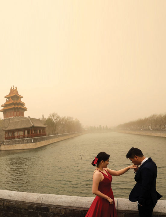 زوجان خلال جلسة تصوير زفافهما بالقرب من مدينة بكين، حيث تعرضت المدينة لعاصفة رملية.   رويترز