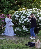 امرأة تلتقط صورة لزميلتها تقف بالقرب من شجيرات الفاوانيا المزهرة في الحديقة النباتية في كييف. (ا ف ب)