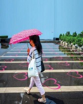 امرأة تمشي تحت المطر فوق منطقة محددة بعلامات للتباعد الاجتماعي في بانكوك . ا ف ب