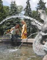فتاتان تستمتعان بمياه النافورة في حديقة وسط العاصمة الأوكرانية كييف  (ا ف ب)