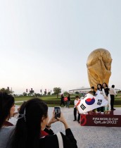 جماهير من كوريا الجنوبية يقفون لالتقاط صورة أمام نسخة طبق الأصل من كأس العالم في قطر -رويترز