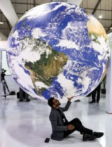 أحد الحضور يقف لالتقاط صورة أسفل عمل فني على هيئة كوكب الأرض خلال مؤتمر المناخ COP27 في مركز شرم الشيخ الدولي للمؤتمرات بمصر  - ا ف ب
